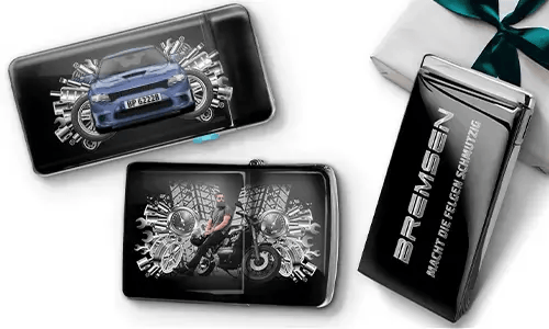 Elegante Geschenkboxen mit einem blauen Auto und einem Biker, umgeben von metallischen Zahnrädern. Eine Box trägt den Text „BREMSEN Macht Die Regeln Schmutzig“, was einen dynamischen, kantigen Ton hinzufügt.