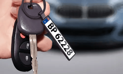 Zwarte nummerplaat sleutelhanger hangt aan autosleutels voor dagelijks gebruik