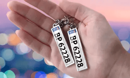 Individuelle Nummernschild-Schlüsselanhänger mit personalisierten Zahlen, in der Hand gehalten