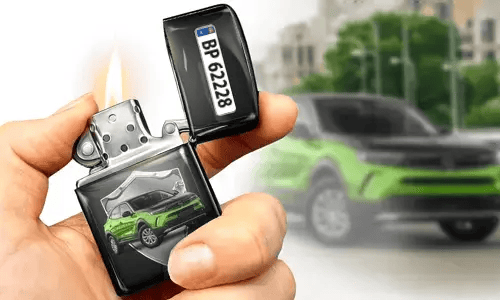 Eine Hand hält ein brennendes Feuerzeug mit einem grünen Auto-Motiv und Kennzeichen. Im Hintergrund ist ein unscharfes grünes Auto zu sehen, das dem Design des Feuerzeugs entspricht.