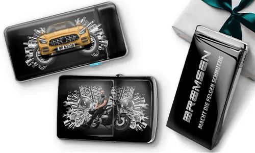 Elegante Geschenkboxen mit einem blauen Auto und einem Biker, umgeben von metallischen Zahnrädern. Eine Box trägt den Text „BREMSEN Macht Die Regeln Schmutzig“, was einen dynamischen, kantigen Ton hinzufügt.