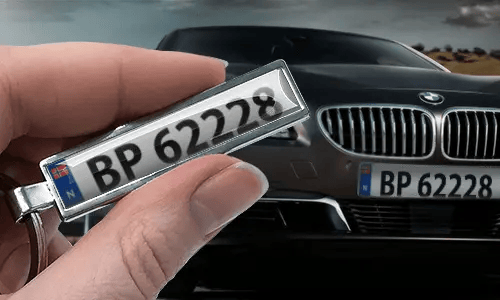 Porte-clés style bande dessinée avec plaque d’immatriculation, tenu dans une main devant une voiture avec des plaques assorties