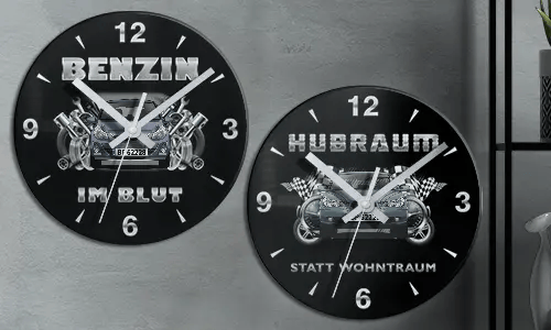 Zwei schwarze Wanduhren mit Autoillustrationen und deutschem Text: BENZIN IM BLUT und HUBRAUM STATT WOHNTRAUM