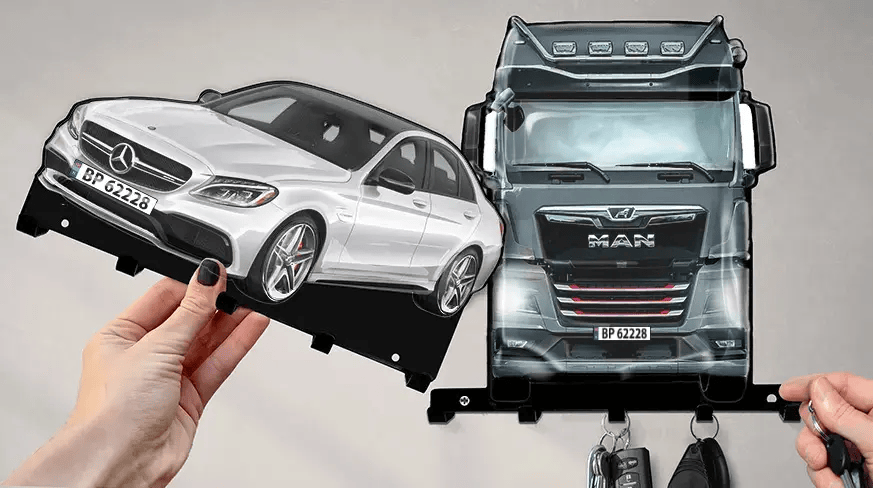 Wandmontierter Schlüsselhalter mit abnehmbaren Formen eines weißen Mercedes-Benz und eines schwarzen MAN-LKWs, jeweils mit Haken für Schlüssel